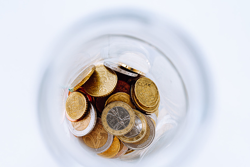 Metal euro coins close-up top view, in glass jar