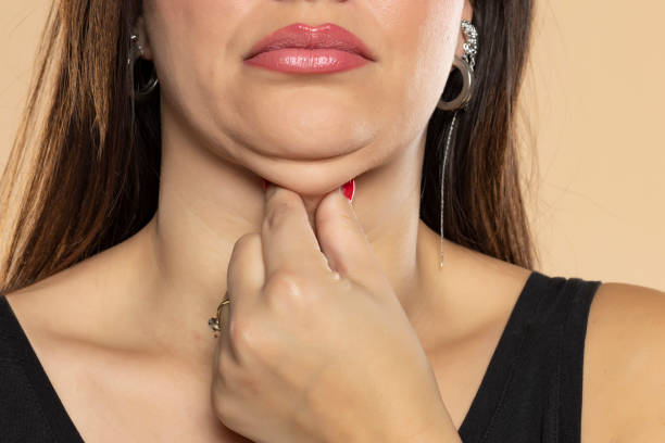 Young woman touches her double chin on beige background, closeup. Front view stock photo
