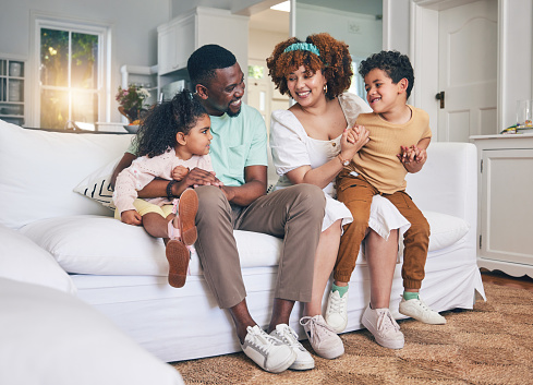 Black family, lounge and living room sofa of a mother, father and children with happiness. Happy, smile and bonding of a mom, dad and young kids together having fun with parent love and support