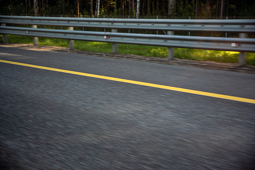 Road barrier, asphalt road and yellow dividing line blurred in motion, road trip concept