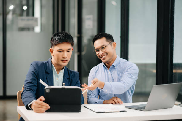 istock Two Asian business workers talking on the smartphone, tablet and using laptop at the office. 1600684420
