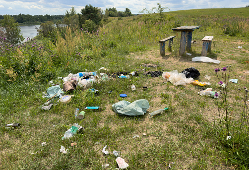 Garbage dump in Illegal location. People throw garbage near lake in nature. Trash at camping resort. Pile of rubbish in nature. Environmental pollution and ecology. Illegal dumping of Garbage.