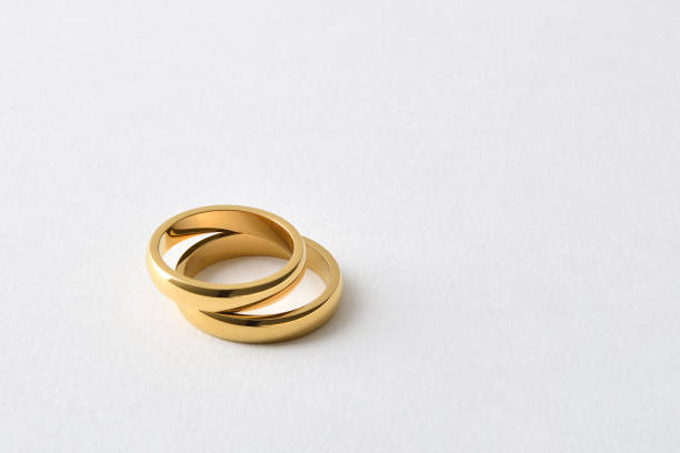 Detail of two gold wedding rings lying one on the other on white isolated background. Elevated view.
