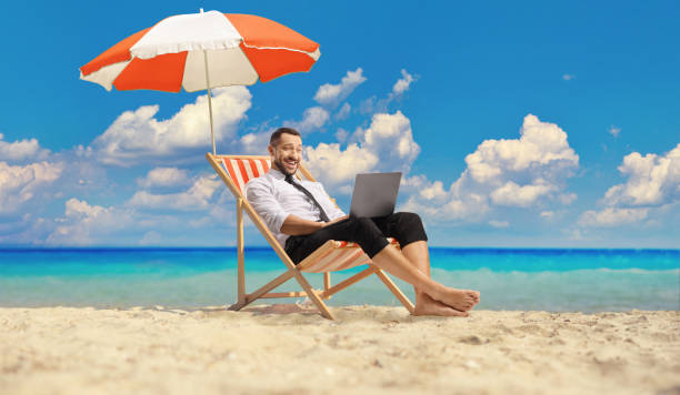 istock Businessman enjoying at the beach with a laptop computer under umbrella 1600706881