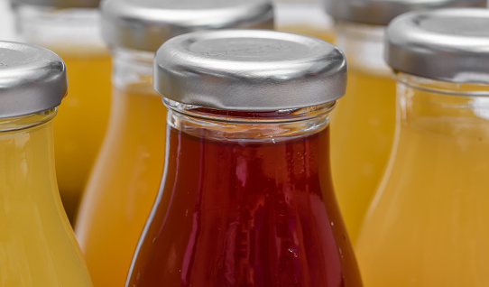 Glass bottles with silver caps, fruit juices, closeup