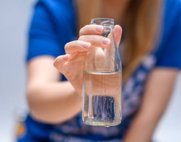 istock Glass bottle with drinking water held in hand 1600712993
