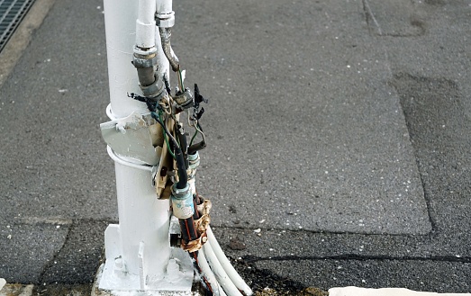 Close-up of an electric pole with cables connect on a street in the car park.