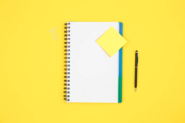 istock Notebook and paper reminder on yellow background, top view. 1600721788