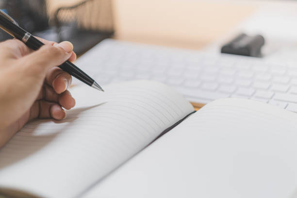 istock Close-up hand holding pen and write on white book 1600733229