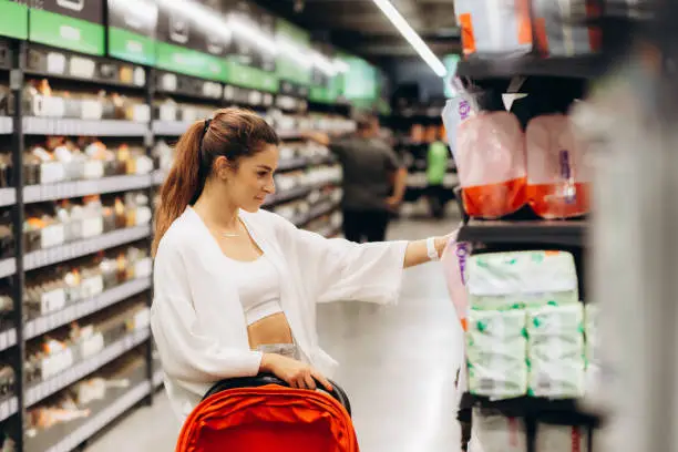 Pregnant woman buys diapers at the supermarket, portrait of young happy mother in shop.