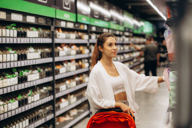 une femme achète des couches pour enfant au supermarché, portrait de jeune mère dans un centre commercial. - diaper shopping human pregnancy supermarket photos et images de collection