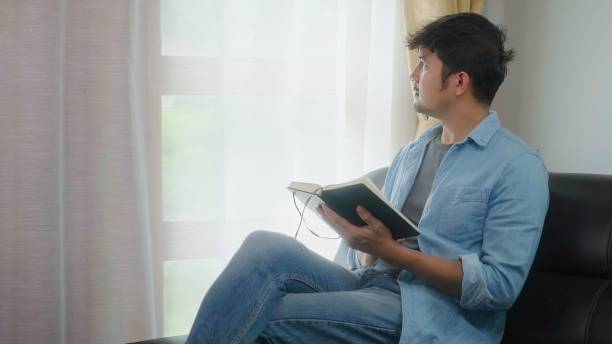 istock freelance asian man sitting in home and reading a book. 1600756096