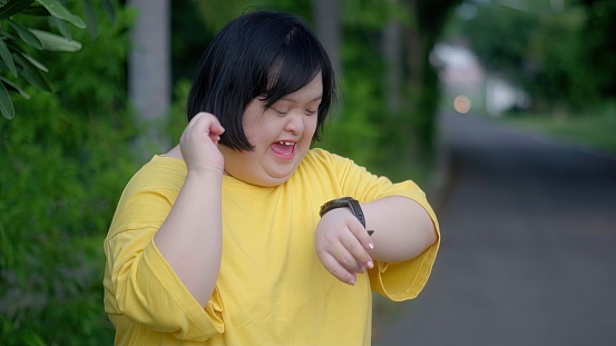 Looking at the clock, an Asian girl with Down syndrome rejoices.As I exercised in the park.