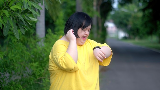 Looking at the clock, an Asian girl with Down syndrome rejoices.As I exercised in the park.