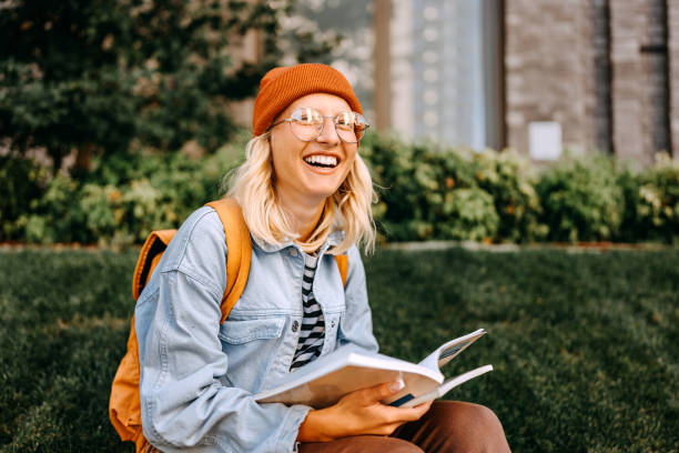 Young cheerful hipster woman studying outdoors in campus