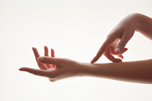 The gentle motion and gesture female hands. Be gentle to yourself metaphorically. Close-up of a young woman softly touching her hands on white background. Elegant and graceful hands with slender graceful fingers.