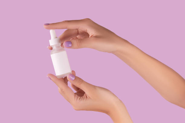 istock Womans hand holding dropper with serum on pastel lavender background 1600824548