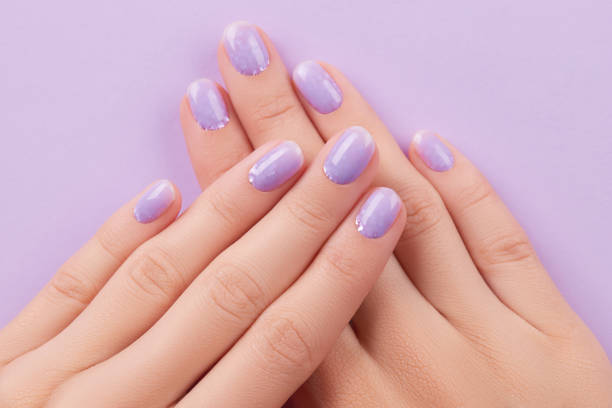 istock Womans hands with trendy lavender manicure. Spring summer nail design 1600830441
