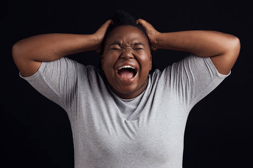 Anger, frustrated and black woman screaming, depression and mental health issue on a dark studio background. Person, emotion and model shouting, anxiety and angry with grief, moody and lose control