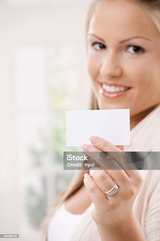 Beautiful young woman holding card Beautiful young woman showink a blank white business card with copy space. Selective focus on card. Click here for more images: 20-24 Years Stock Photo