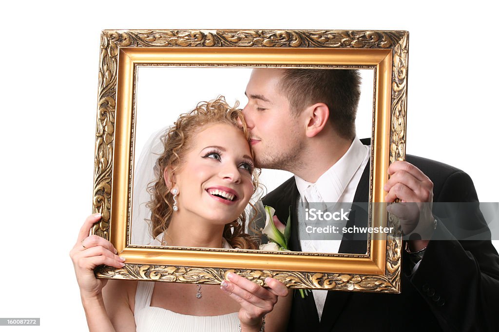 Bride and groom holding up empty picture frame around faces studio shot Photography Stock Photo