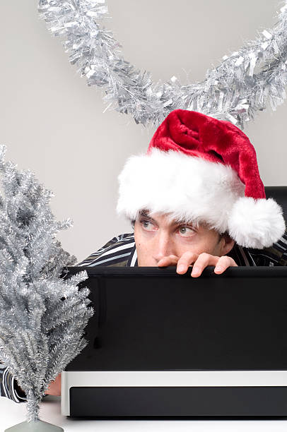 homem esconde atrás de computador portátil com chapéu de natal - hidding imagens e fotografias de stock