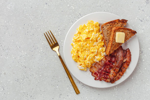 traditional scrambled egg breakfast with bacon and toast