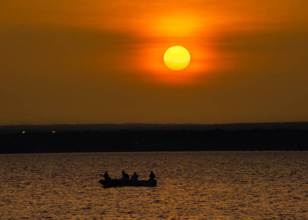 Sunset at coastline with sun and a boat