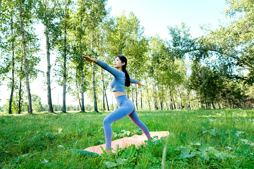 Portrait of a young woman doing yoga in the garden for a workout. Concept of lifestyle fitness and healthy. Asian women are practicing yoga in the park.