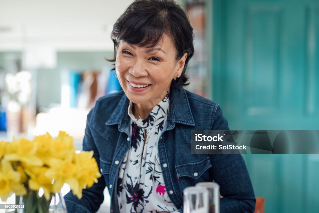 Portrait of a Woman in Her Kitchen Amidst the familiar surroundings of her kitchen, the woman stands with a sense of purpose, her posture a reflection of the confidence. Senior Women Stock Photo