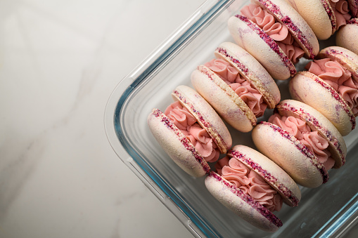 Pink French or Italian macarons in transparent baking glass form. Space for text. Homemade bakery style.