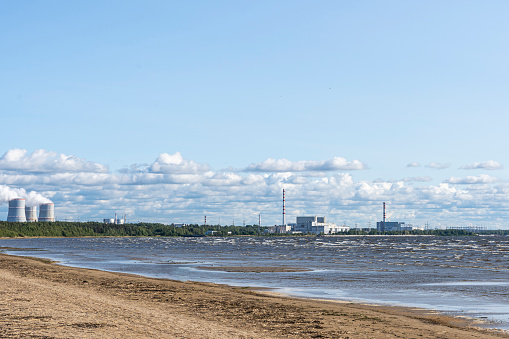 Nuclear power plant on the shore of the Gulf of the Sea. Beaches seashore against the background of floating cooling towers of a nuclear power plant