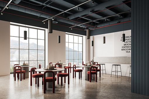 Corner of stylish coffee shop with white and dark blue walls, concrete floor, white bar counter with stools and round tables with red chairs standing near big windows with mountain view. 3d rendering
