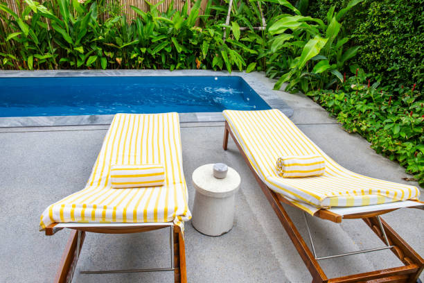 istock Pool chairs and beautiful blue water with green tree in the background. 1600947605