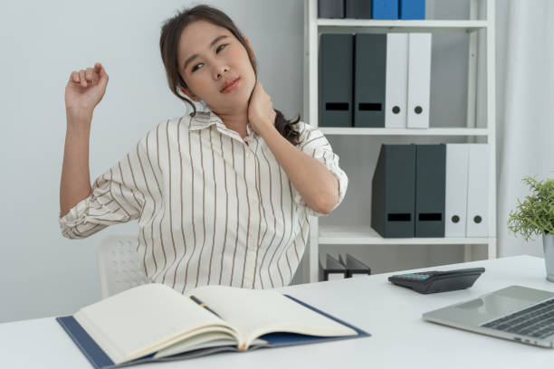 síndromes de consultório, mulher massageando dor no pescoço devido ao trabalho e usando um computador, composto digital de uma coluna focada de dor no pescoço e sintomas de dor no ombro , lesões, cuidados de saúde, médico, miosite - physical injury backache occupation working - fotografias e filmes do acervo