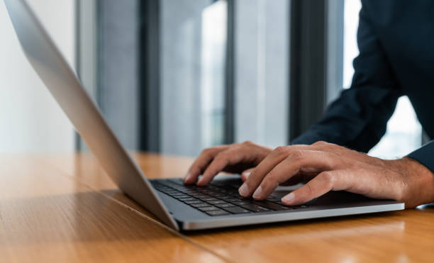 istock Man in blue shirt typing on laptop in office 1600960739