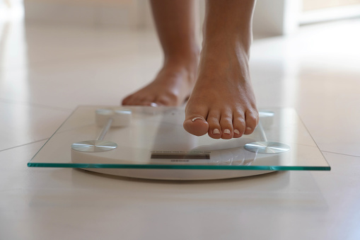 Close-up of female foot stepping on weight scale. Healthy lifestyle, diet and sport concept.
