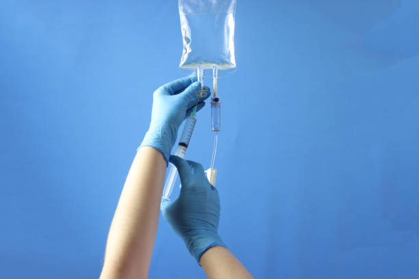 bolsa de medicamentos con un equipo de infusión conectado a la administración del medicamento al paciente. profesional sosteniendo la bolsa para infundir el medicamento con una jeringa - solución salina fotografías e imágenes de stock