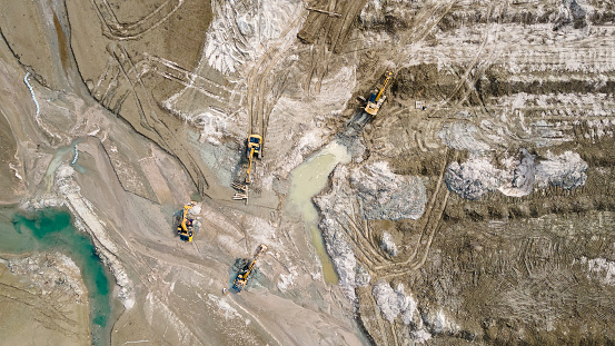 Excavators on the shallow lake bed. Cleaning works. View from a drone