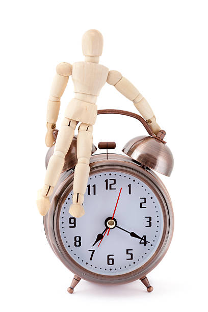 istock Wooden dummy sitting on old-styled metal alarm clock. 160098872