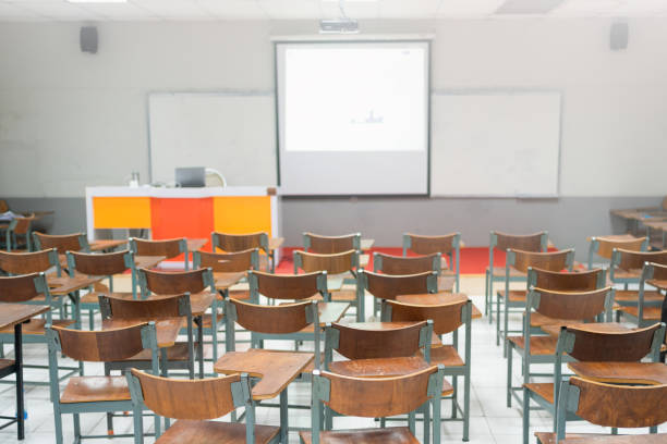 Empty school classroom with many wooden chairs. Wooden chairs in classroom. Wooden arranged in classroom. Empty classroom with vintage tone wooden chairs. Back to school concept