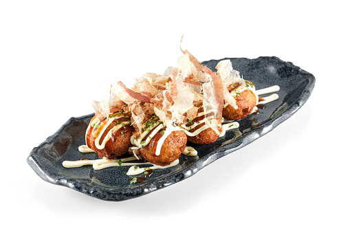 Plate with Japanese deep fried wheat octopus balls of Takoyaki topped with bonito flakes isolated on white background