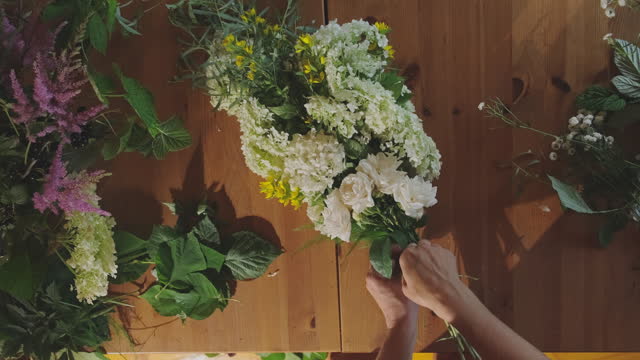 Florist hands making summer bouquet of flowers working in flower shop.