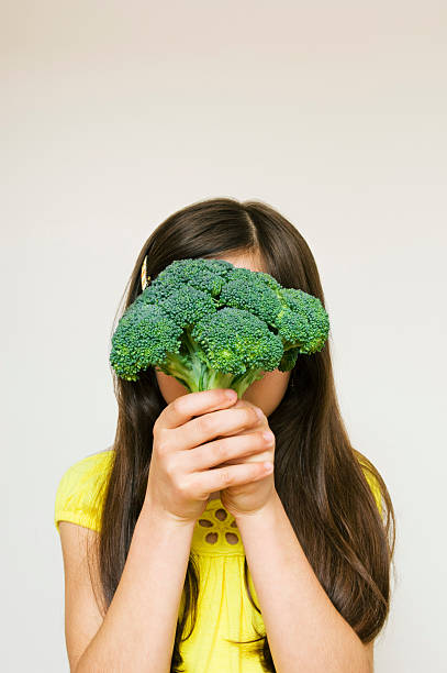 istock Young Girl Hiding Behind Broccoli 160102033