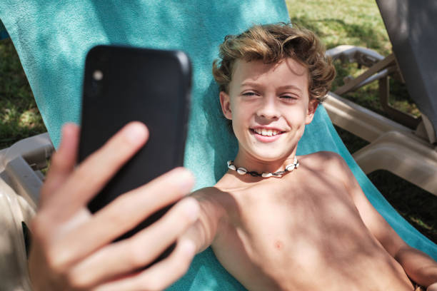 istock Cheerful boy taking selfie on smartphone in resort garden 1601021446