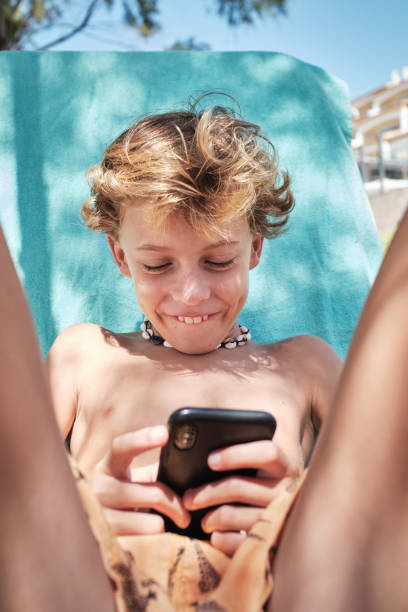 istock Cheerful boy browsing phone in hotel garden 1601022526