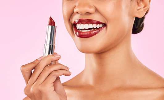 Lipstick, red lips and woman with smile, beauty and skin with makeup closeup isolated on pink background. Female model, cosmetic product and shine, happiness and cosmetology with glow in studio