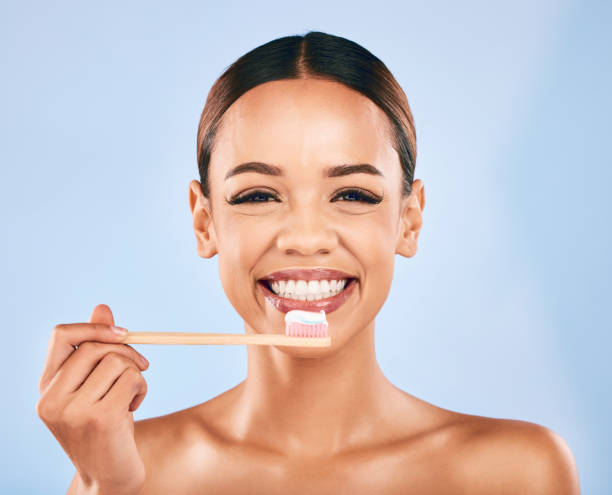 donna felice, sorriso ritratto e spazzolino da denti per l'igiene dentale o la pulizia su uno sfondo blu dello studio. persona femminile o modello sorridente con spazzolino da denti per denti puliti, cura orale o gengivale e della bocca - lifestyles toothy smile care beauty foto e immagini stock