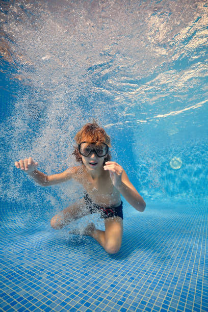 istock Boy in goggles swimming in blue clean water 1601037780
