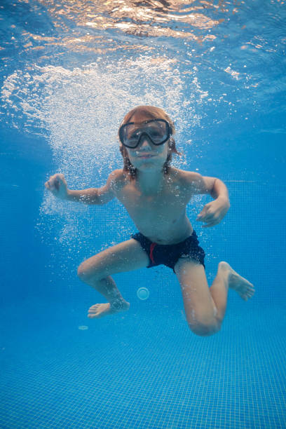 istock Carefree boy swimming underwater in pool with clear water 1601038920